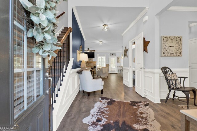 entryway with crown molding, stairs, and wood finished floors