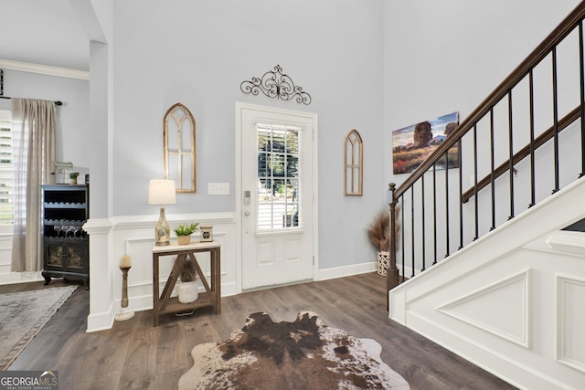 foyer featuring a high ceiling, ornamental molding, stairs, and wood finished floors