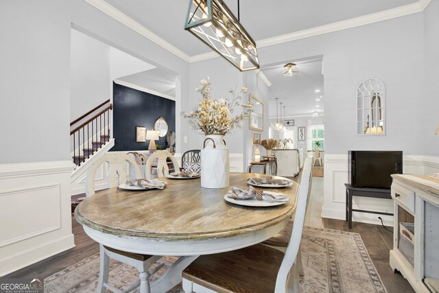 dining space featuring ornamental molding, dark wood finished floors, wainscoting, and stairway