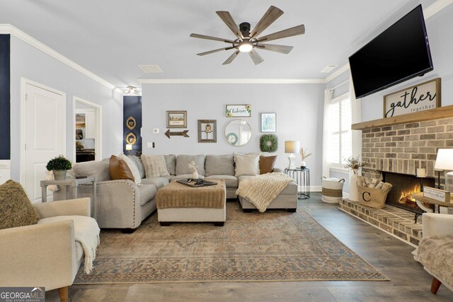 living room with crown molding, a fireplace, a ceiling fan, wood finished floors, and visible vents