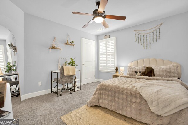 carpeted bedroom featuring baseboards, arched walkways, and ceiling fan