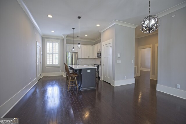 4143 N Swann St, Covington, GA 30014 - kitchen featuring ornamental molding, a breakfast bar, a center island with sink, light countertops, and appliances with stainless steel finishes