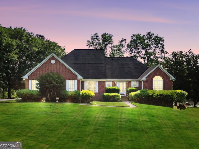 single story home featuring a yard and brick siding