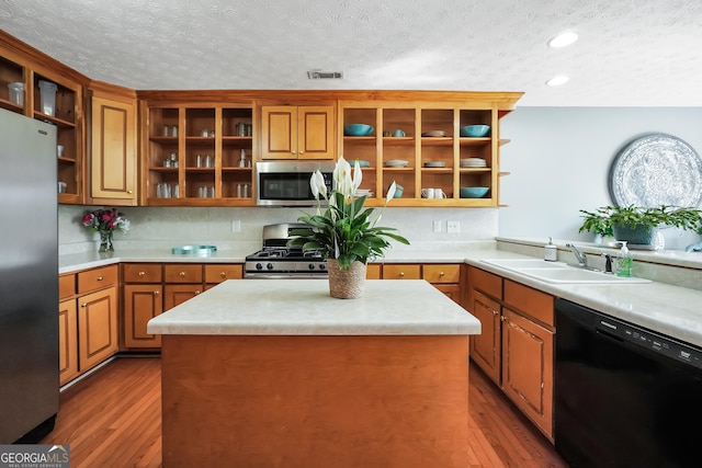 kitchen featuring a sink, open shelves, appliances with stainless steel finishes, and wood finished floors