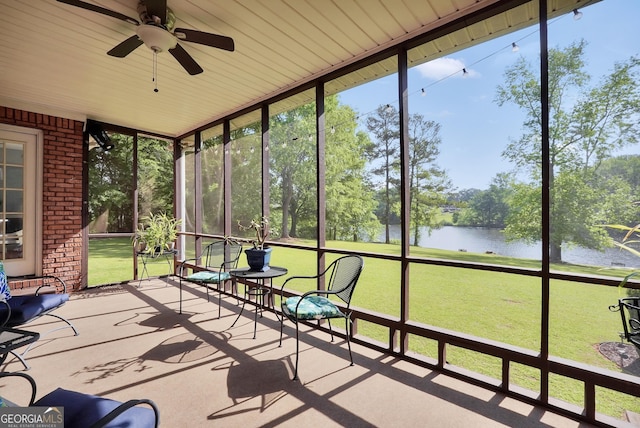 unfurnished sunroom featuring a water view and ceiling fan