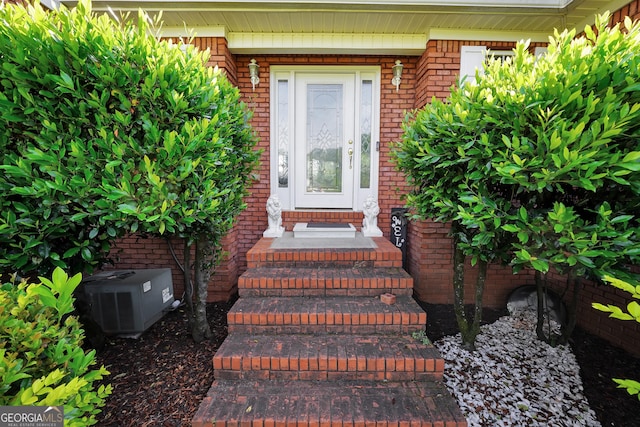 property entrance with brick siding and central AC unit