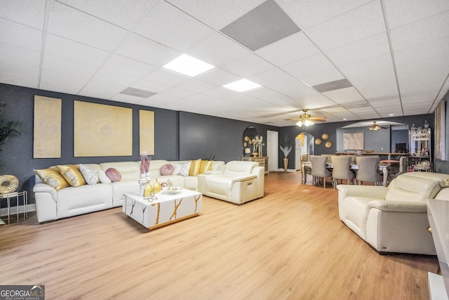 living area featuring a ceiling fan, a drop ceiling, and wood finished floors
