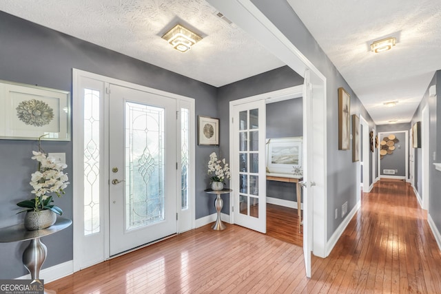 entrance foyer with plenty of natural light, a textured ceiling, baseboards, and hardwood / wood-style floors