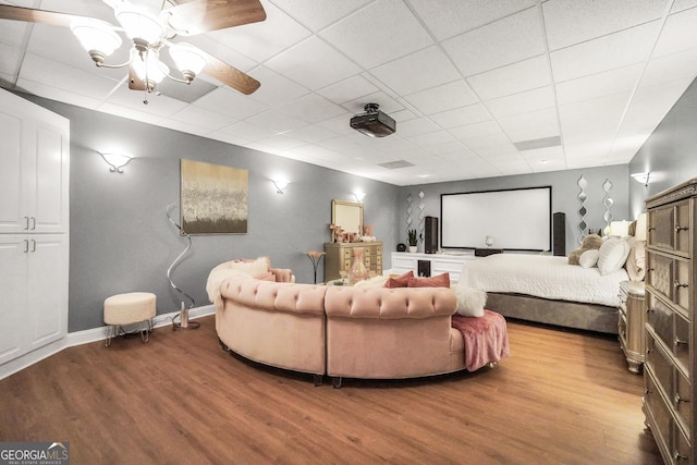 cinema featuring a ceiling fan, a paneled ceiling, and wood finished floors