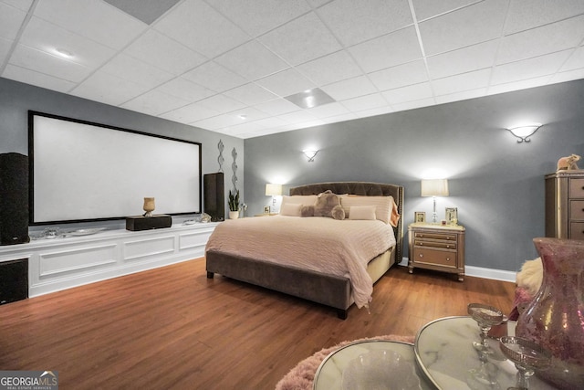 bedroom featuring baseboards, a paneled ceiling, and wood finished floors
