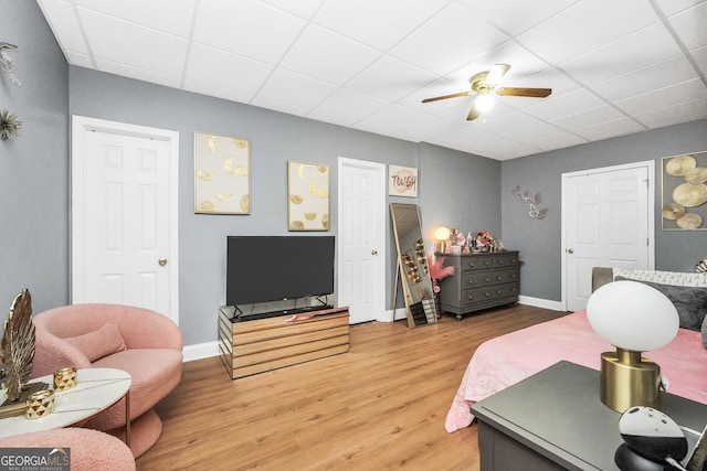 bedroom with light wood-type flooring, a paneled ceiling, and baseboards