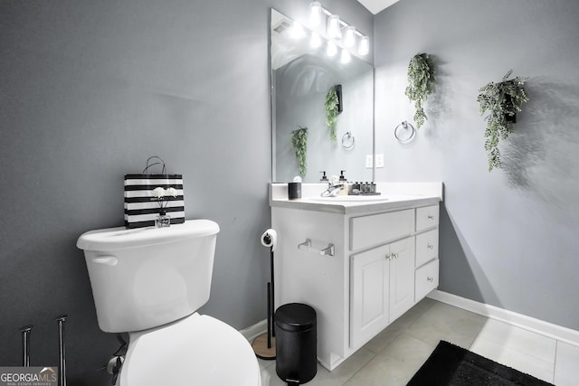 half bathroom featuring vanity, baseboards, tile patterned floors, and toilet