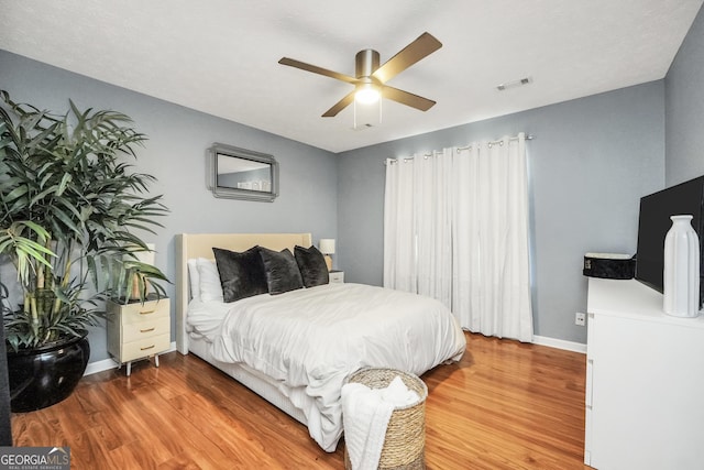 bedroom with baseboards, ceiling fan, wood finished floors, and visible vents