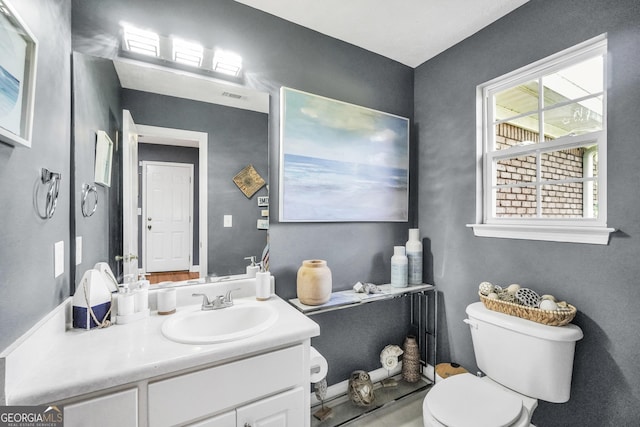 half bathroom with vanity, visible vents, and toilet