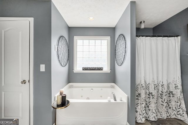 bathroom featuring a jetted tub, a textured ceiling, and a shower with curtain