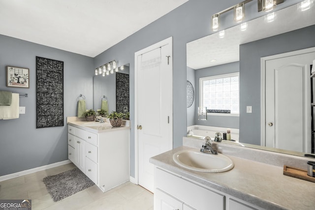 full bathroom with baseboards, a sink, a garden tub, and two vanities