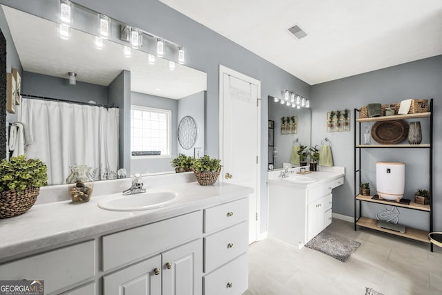 full bathroom featuring a sink, baseboards, tile patterned flooring, and two vanities
