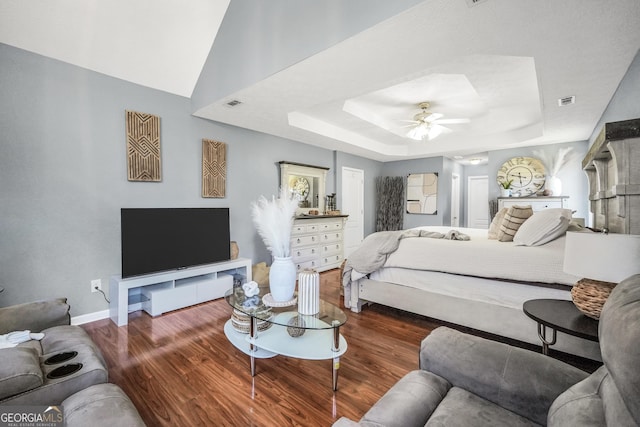 bedroom featuring baseboards, visible vents, wood finished floors, and a raised ceiling