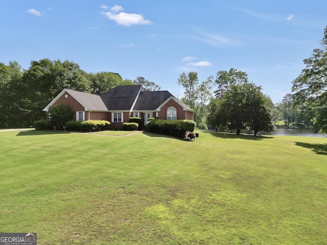 view of front of property featuring a water view, brick siding, and a front yard