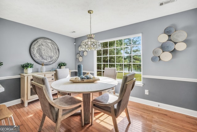 dining area with light wood-style floors, baseboards, a notable chandelier, and visible vents