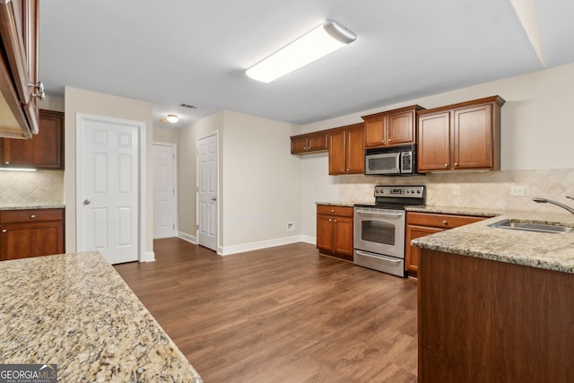 2055 Hickory Station Cir, Snellville, GA 30078 - kitchen with light stone countertops, appliances with stainless steel finishes, a sink, visible vents, and dark wood-style floors