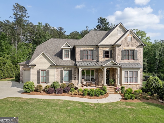 craftsman inspired home featuring a porch, a front yard, an attached garage, and concrete driveway