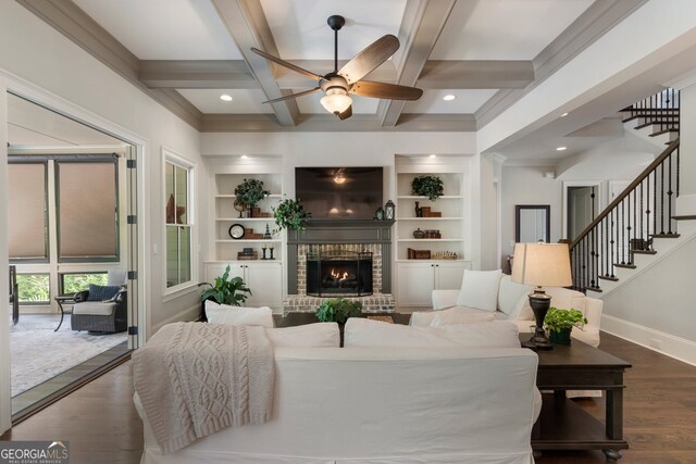 living area with coffered ceiling, a ceiling fan, dark wood finished floors, baseboards, and a brick fireplace