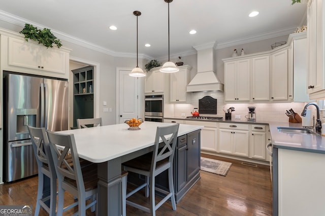 kitchen with a sink, stainless steel appliances, a center island, premium range hood, and a kitchen breakfast bar