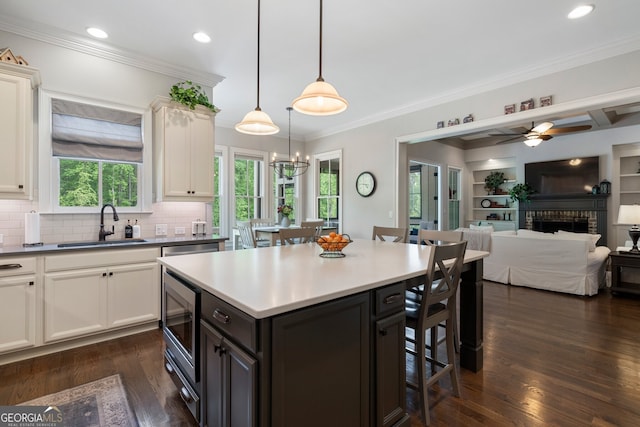 kitchen featuring a breakfast bar, stainless steel microwave, open floor plan, healthy amount of natural light, and crown molding
