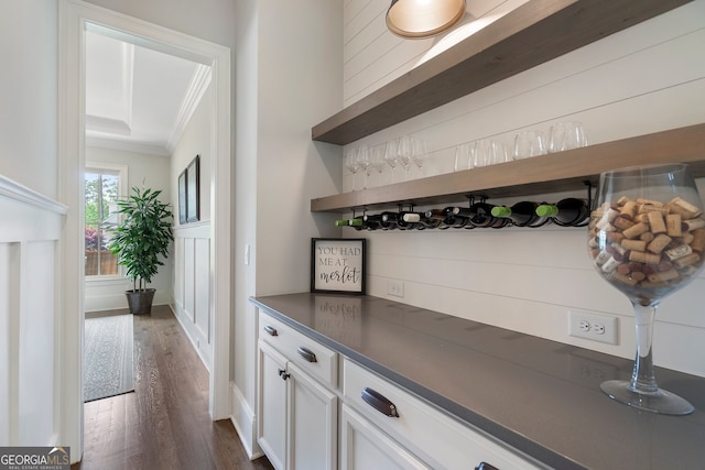indoor dry bar featuring ornamental molding and dark wood-style flooring