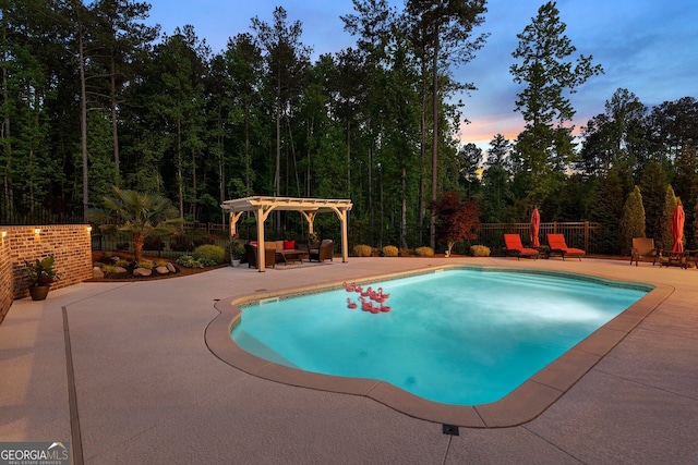 pool at dusk featuring a patio, a pergola, fence, and a forest view