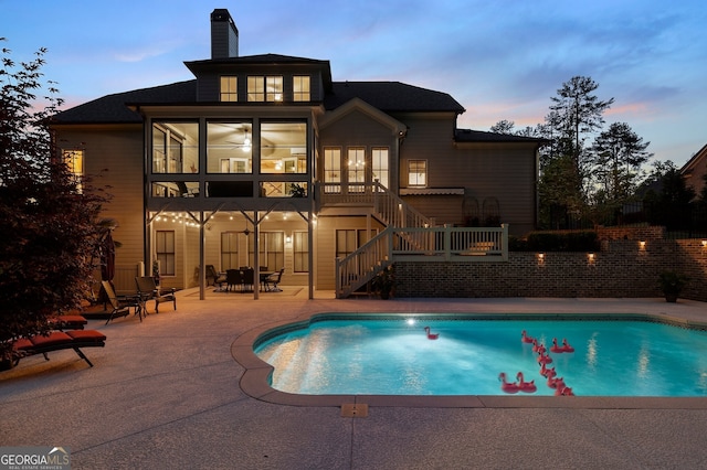 pool at dusk with stairs, a patio, and an outdoor pool