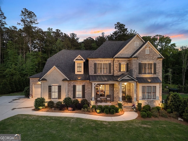 view of front facade featuring covered porch, concrete driveway, a front lawn, an attached garage, and brick siding