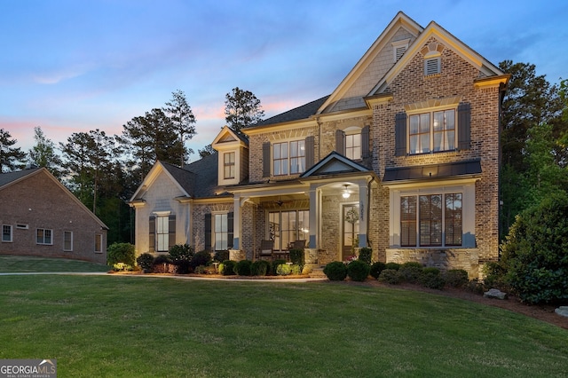 view of front of house with a front yard, covered porch, brick siding, and stone siding