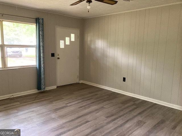 218 Lassiter Dr, Dublin, GA 31021 - spare room with ornamental molding, wood walls, baseboards, ceiling fan, and dark wood finished floors