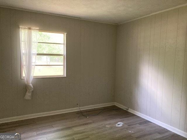 218 Lassiter Dr, Dublin, GA 31021 - unfurnished room with baseboards, wood walls, a textured ceiling, and dark wood-style floors