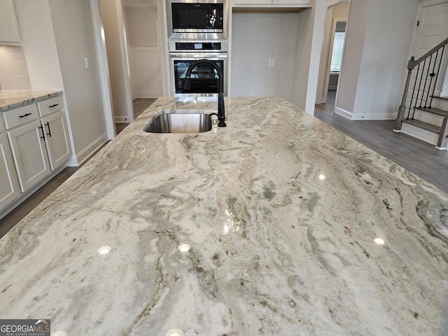 457 Banff Dr, Winder, GA 30680 - kitchen featuring appliances with stainless steel finishes, light stone counters, white cabinets, dark wood-style flooring, and backsplash