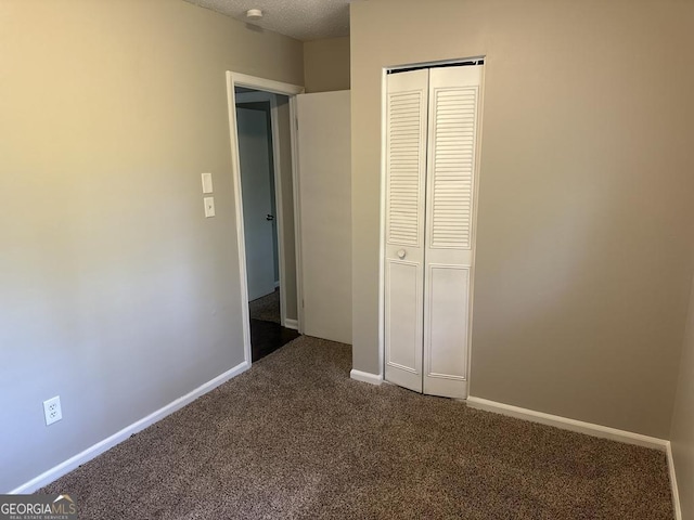 1685 Pheasant Dr, Jonesboro, GA 30238 - unfurnished bedroom featuring baseboards, a closet, dark carpet, and a textured ceiling
