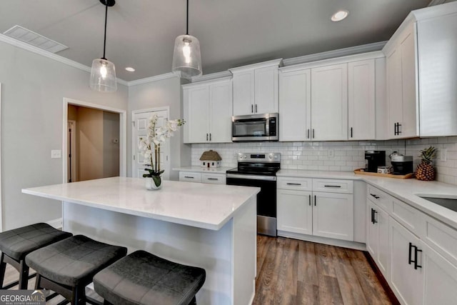 5299 Noble Village Way, Lilburn, GA 30047 - kitchen featuring appliances with stainless steel finishes, a kitchen bar, white cabinetry, and visible vents