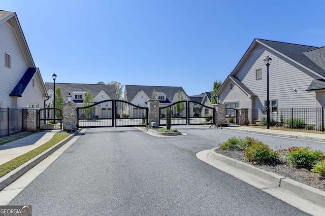 5299 Noble Village Way, Lilburn, GA 30047 - view of road with curbs, street lighting, a residential view, a gate, and sidewalks