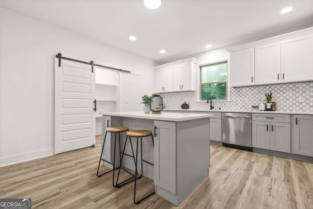 921 Cone Rd, Forest Park, GA 30297 - kitchen featuring stainless steel dishwasher, a barn door, light wood-type flooring, backsplash, and a center island