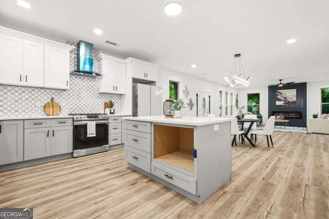 921 Cone Rd, Forest Park, GA 30297 - kitchen featuring stainless steel range, freestanding refrigerator, wall chimney exhaust hood, light countertops, and plenty of natural light