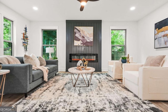 living area featuring a ceiling fan, a glass covered fireplace, wood finished floors, and recessed lighting