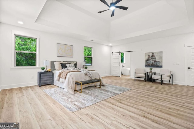bedroom with recessed lighting, a barn door, a raised ceiling, and wood finished floors