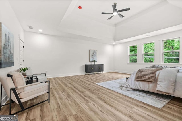 bedroom with visible vents, wood finished floors, a tray ceiling, and multiple windows