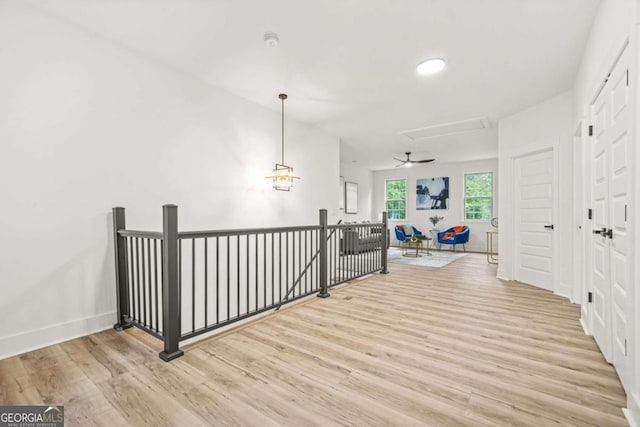 hall featuring baseboards, wood finished floors, and an upstairs landing