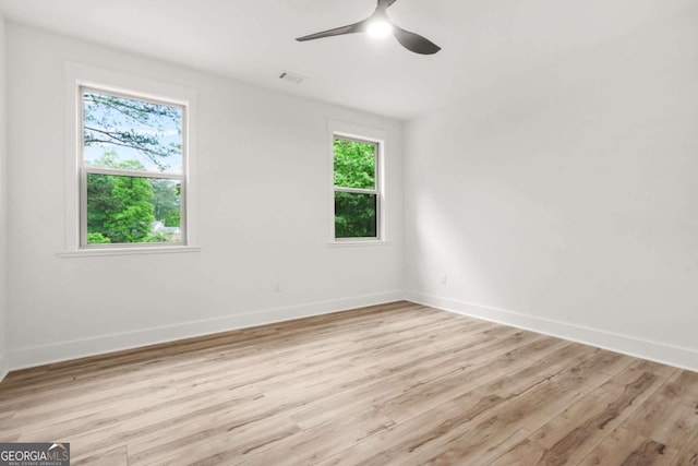 empty room with baseboards, visible vents, ceiling fan, and light wood finished floors