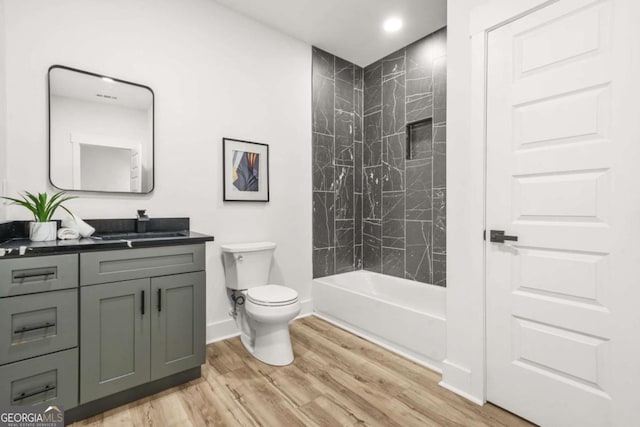 bathroom featuring vanity, wood finished floors, toilet, baseboards, and washtub / shower combination