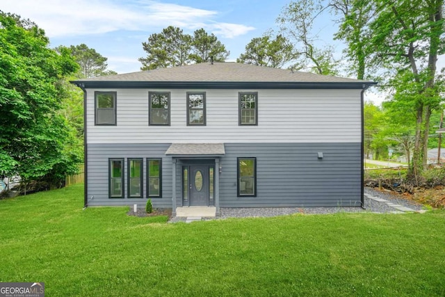rear view of property featuring a lawn and a shingled roof
