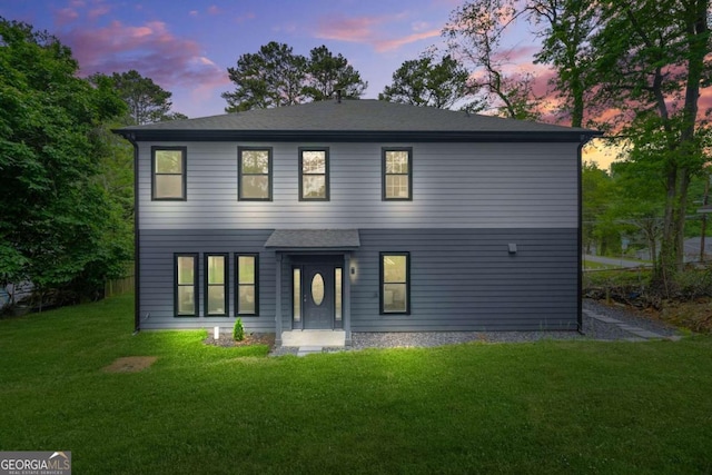 view of front of house with roof with shingles and a front yard